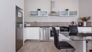 Et moderne køkken med hvide skabe, rustfrie stålapparater og et spisebord i glas.
