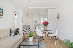 Uma sala de estar moderna com um sofá, uma mesa de centro e uma área de jantar com cadeiras e uma mesa de vidro.