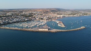 An aerial view of a coastal town with a marina, residential areas, and a prominent building at the marina's center.