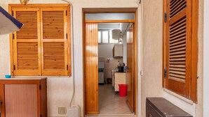 A hallway with wooden doors, a kitchen in the background, and a red trash bin.