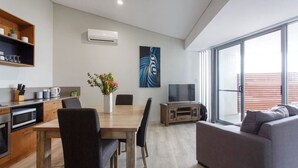 Ett modernt vardagsrum med en matplats, en platt-TV och ett stort fönster.