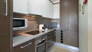 Una cocina moderna con armarios blancos, electrodomésticos de acero inoxidable y un microondas.