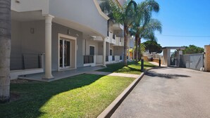 Un edificio residencial de varios pisos con balcones, un camino de entrada pavimentado y un césped bien cuidado.