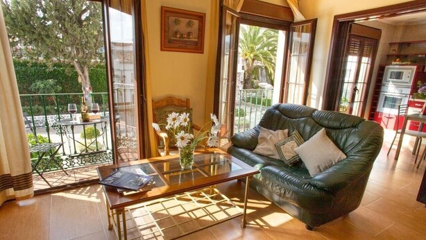 A living room with a leather sofa, a glass coffee table, and a view of a balcony with outdoor furniture. - Holiday Home "Casa Montelucía" with Mountain View, Terrace & Wi-Fi (Montecorto)