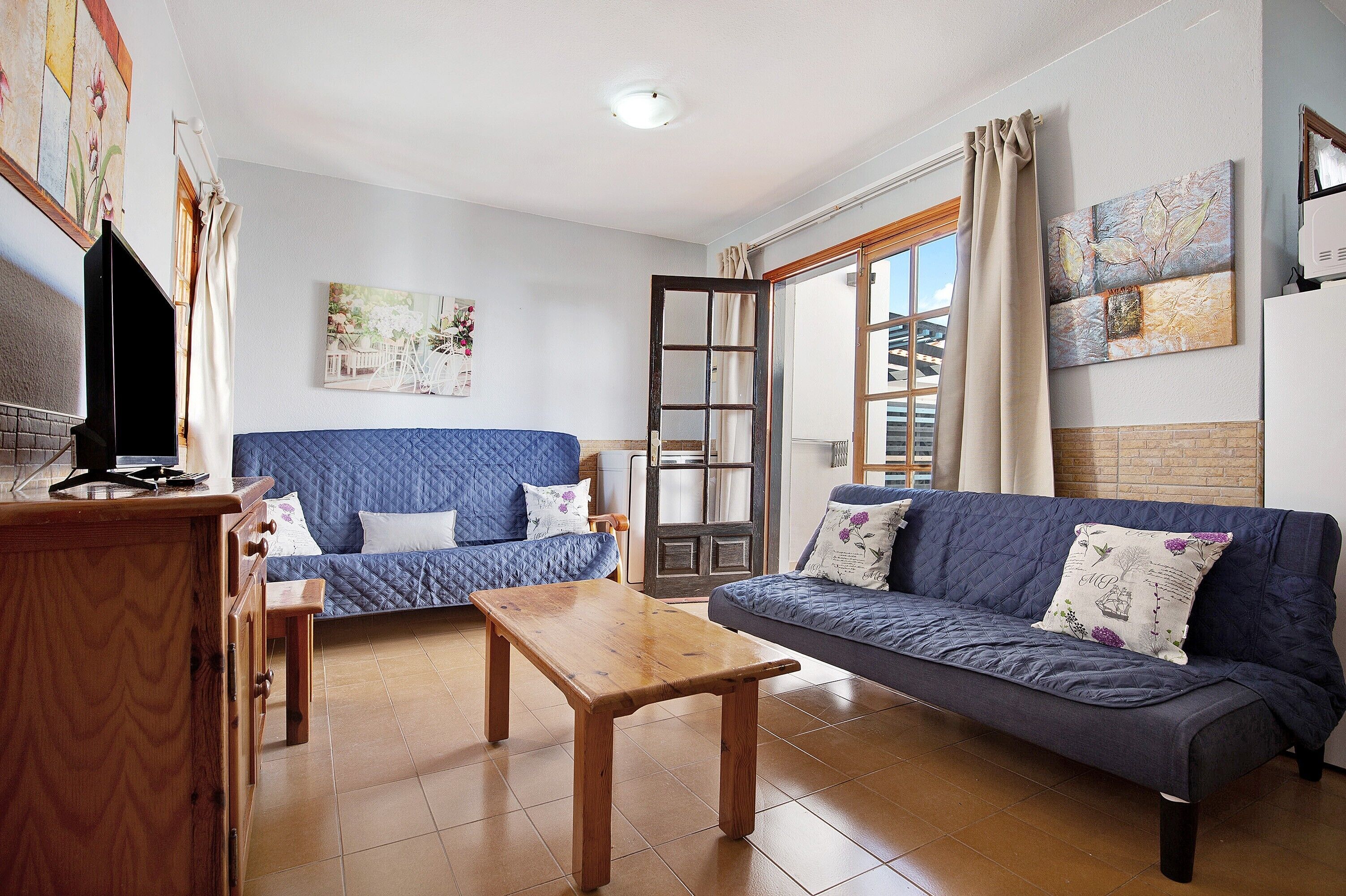 A living room with two sofas, a wooden table, a TV, and artwork on the walls.
