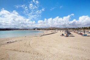 Una playa con cielos despejados, una orilla arenosa y sombrillas de playa.