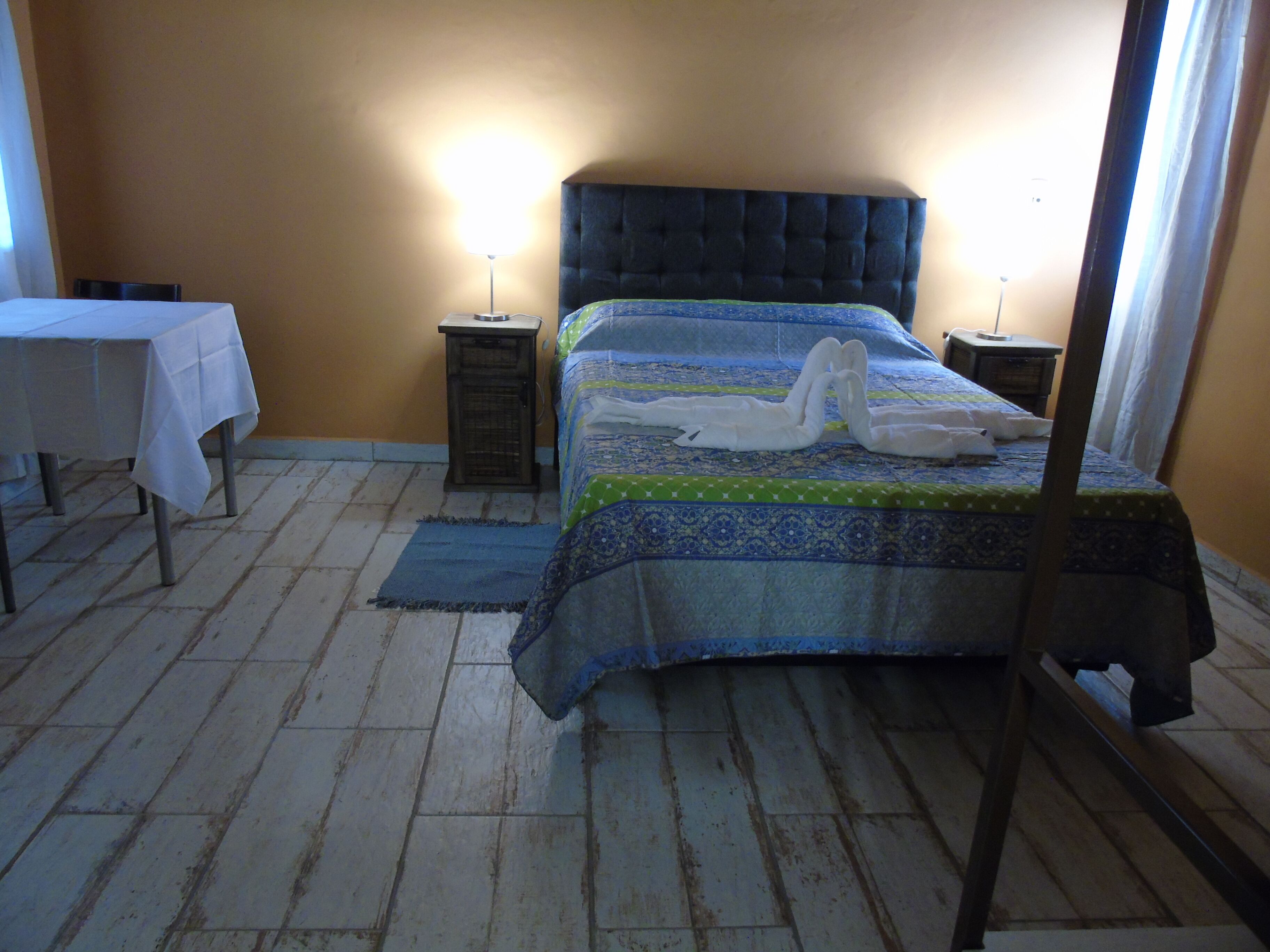 Un dormitorio con una cama, dos mesitas de noche, una mesita pequeña y un espejo.