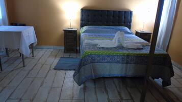 Un dormitorio con una cama, dos mesitas de noche, una mesita pequeña y un espejo.