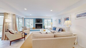 A living room with a fireplace, two sofas, a coffee table, and a TV.