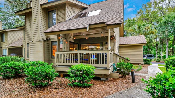 A multi-story house with a porch, surrounded by greenery.