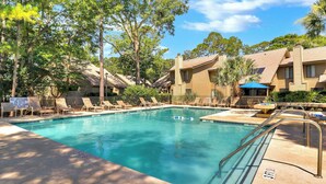 A swimming pool surrounded by lounge chairs and a building with a tiled roof.