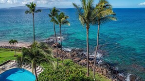 A coastal view with a clear blue sky, a swimming pool, and palm trees. - TOP FLOOR-STUNNING OCEAN VIEWS-WELL EQUIPPED-ALL NEW FURNISHINGS (Kihei)