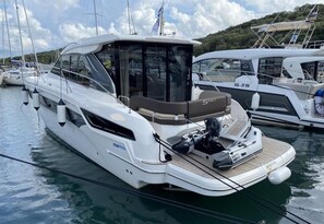 A white motor yacht with a covered seating area and a wakeboard on the deck.