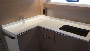 A compact kitchen with a white countertop, a built-in sink, and a black induction cooktop.