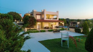 Une maison moderne à deux étages dotée d’un patio, d’un espace salon extérieur et d’une piscine.