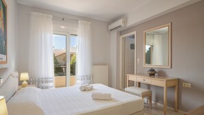 Une chambre d’hôtel avec un lit, un bureau, une chaise, un miroir et une fenêtre avec des rideaux.