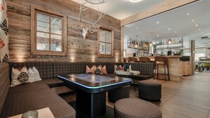 Un área de descanso moderna con mesa de billar, asientos y bar.