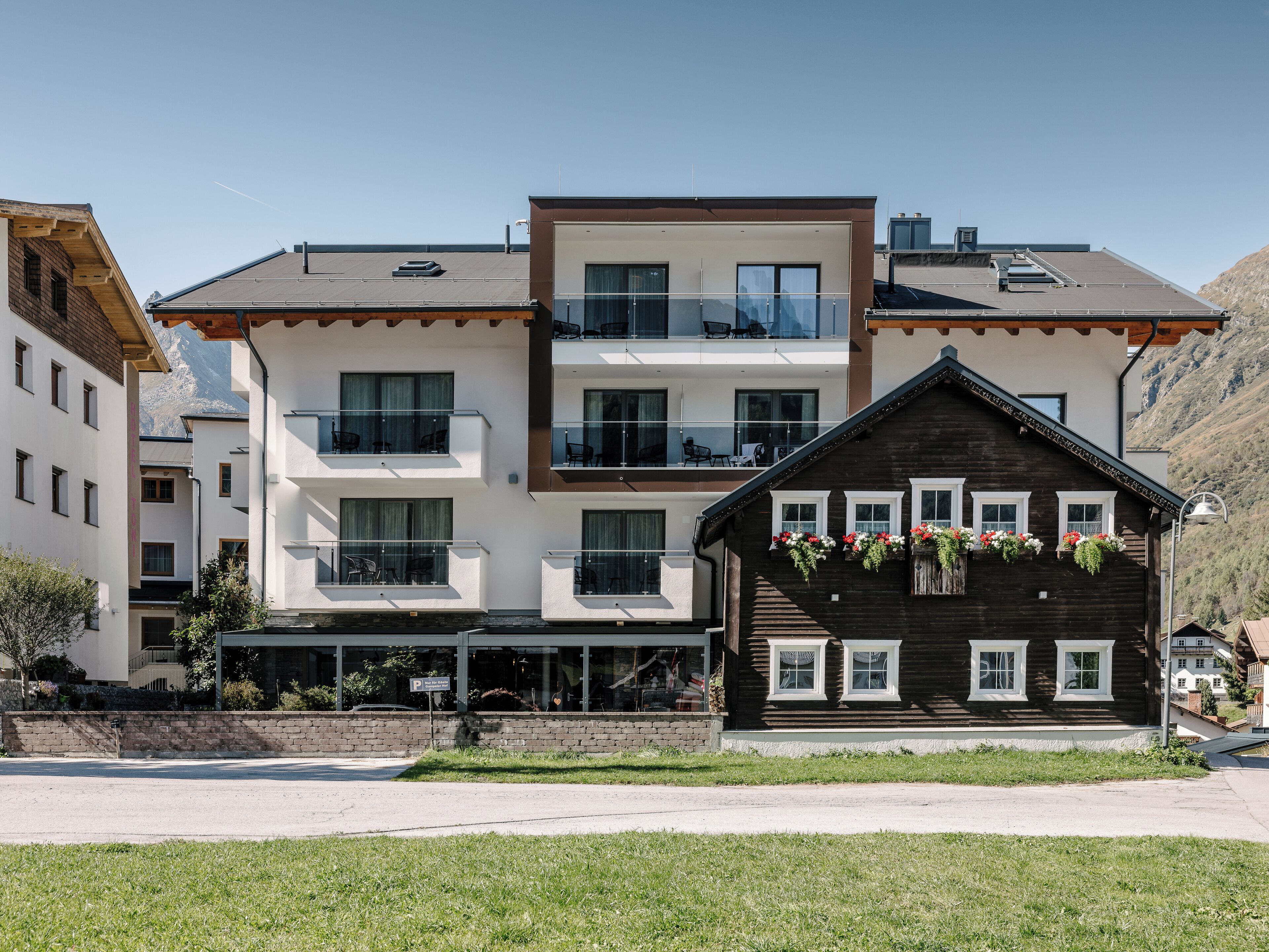 Un hotel de varios pisos con balcones, fachada de madera y jardineras con flores.