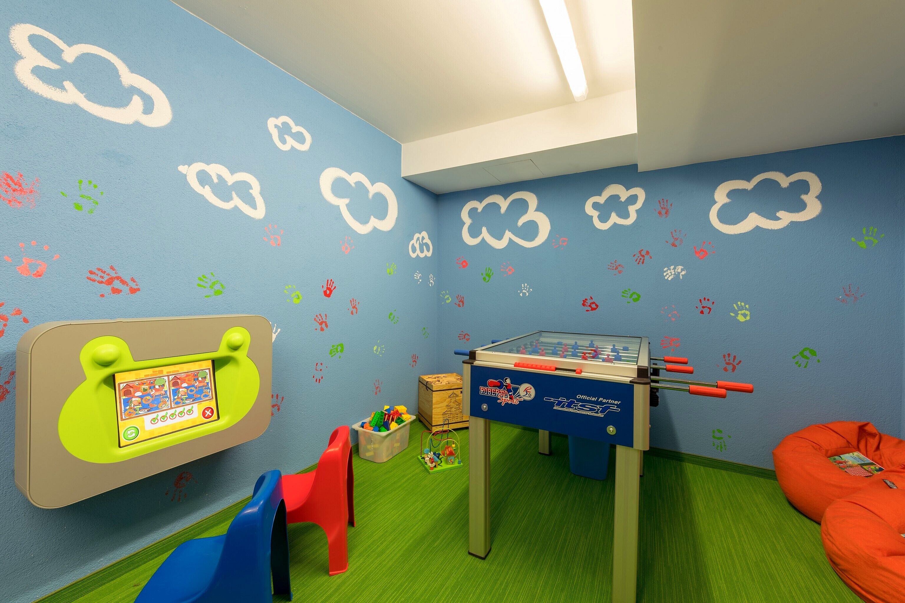 A children's playroom with a foosball table, a red chair, and a bean bag.