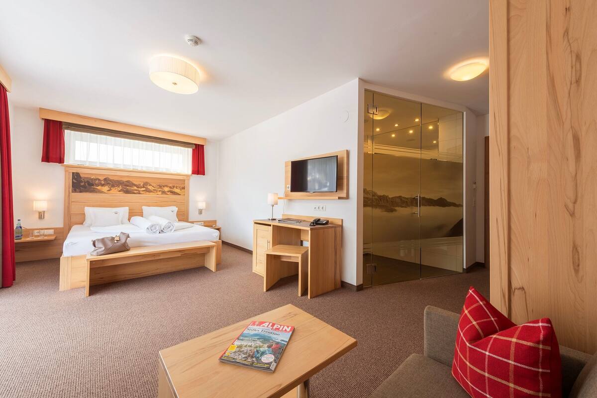 A modern hotel room with a bed, desk, and TV.