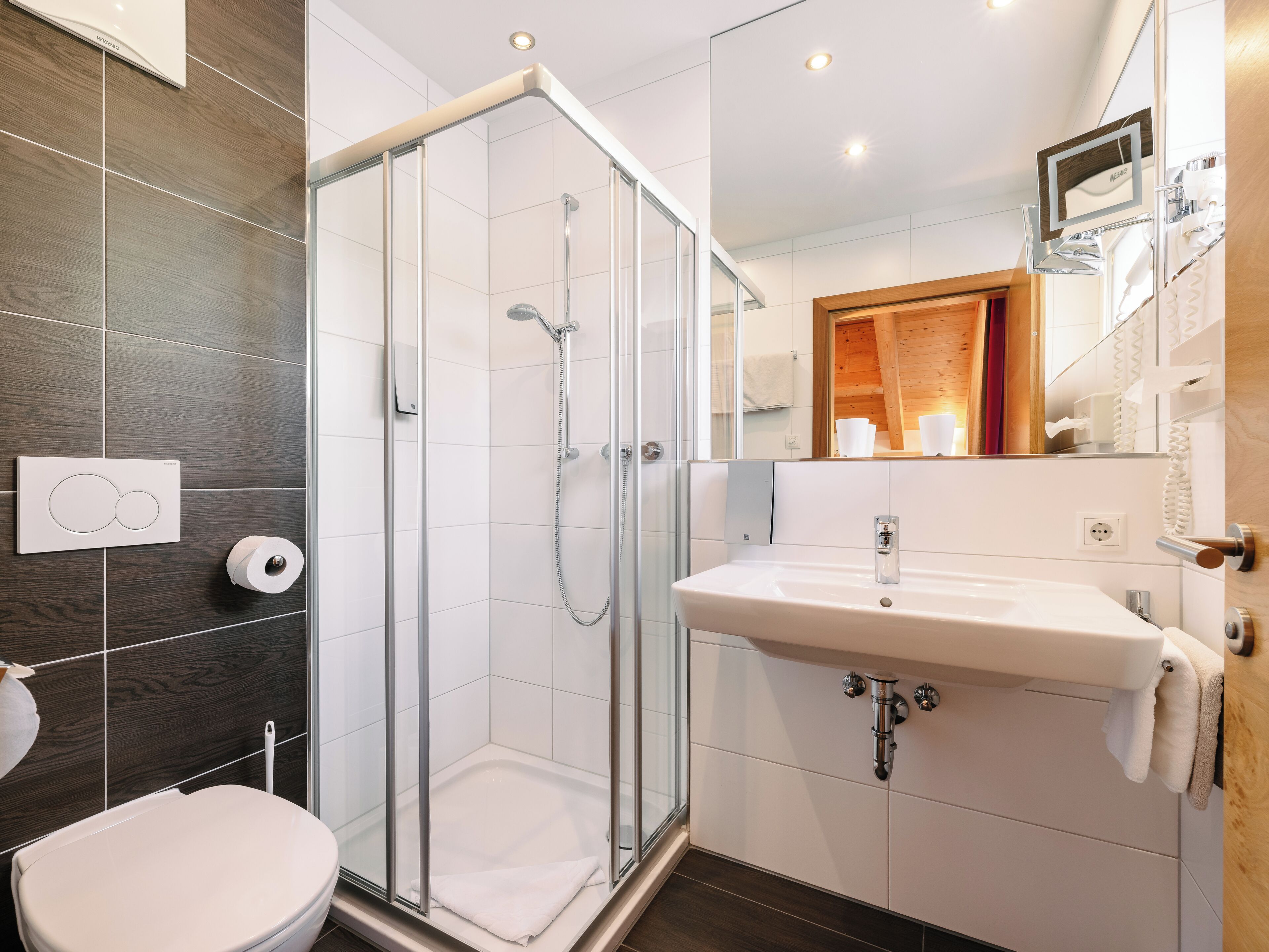 Un baño moderno con ducha cubierta por vidrio, un lavabo blanco y un inodoro.