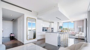 Un interior moderno con una isla central, un espejo grande y una zona de estar con sofá y sillones.