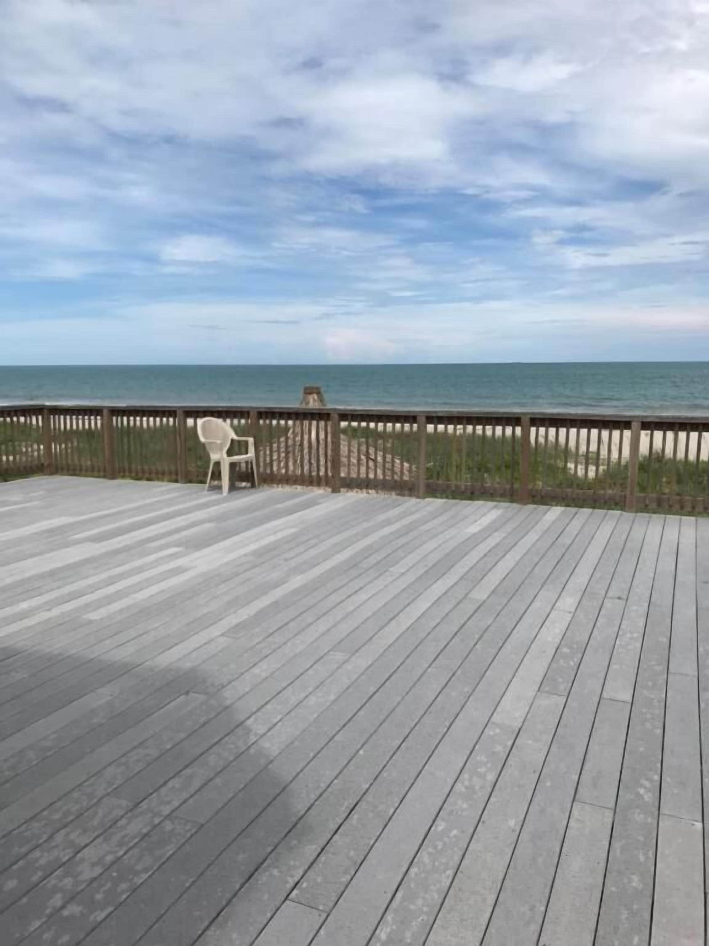 A wooden deck with a view of the ocean and beach.