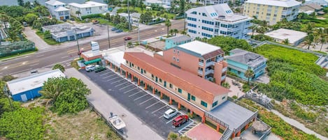 Vista aérea de un hotel costero con estacionamiento, una terraza frente a la playa y vistas al mar.