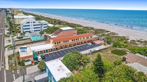 Un motel con estacionamiento, vista al mar y una carretera con coches.