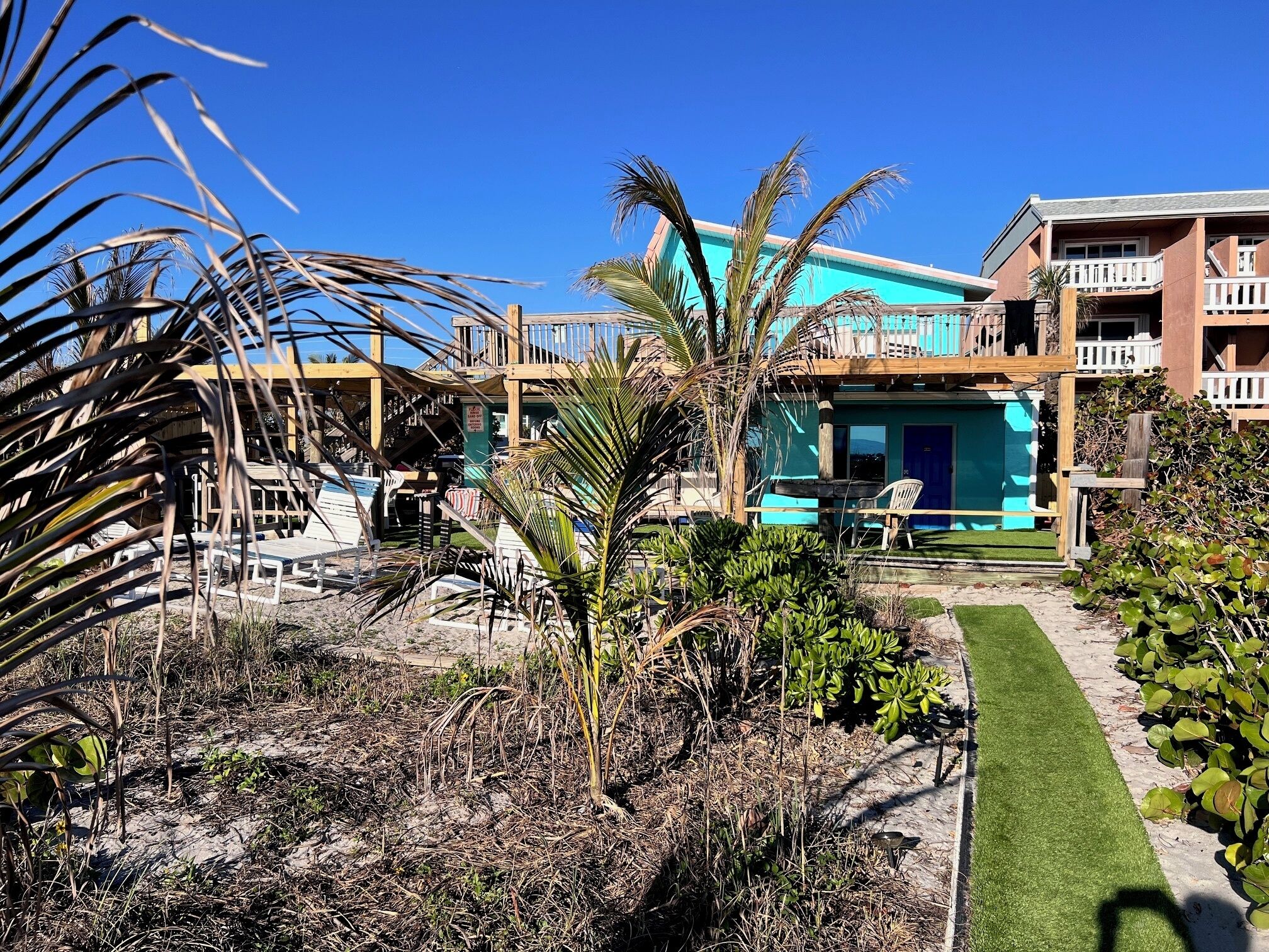 A beachfront property with a pool, outdoor seating, and a wooden deck.
