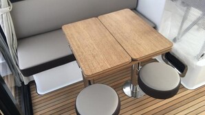 Interior compacto de RV com sofá, uma mesa de madeira pequena e dois banquinhos redondos.