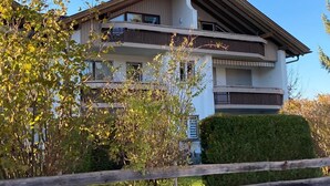 Ein mehrstöckiges Wohngebäude mit Balkonen, ein Holzzaun im Vordergrund und ein klarer Himmel.