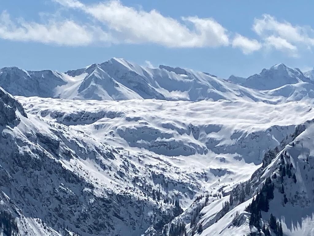 Een bergachtig landschap met besneeuwde toppen en een heldere lucht.
