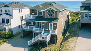 Een tweelaags huis met een balkon, een rond raam en uitzicht op de oceaan.