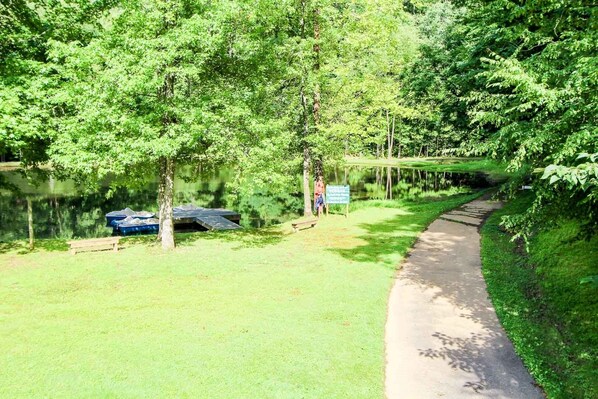 A serene park area with a walking path, a small dock, and a signboard.