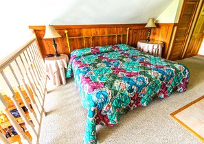 A bedroom with a bed, two bedside tables, a wooden headboard, and a balcony railing.