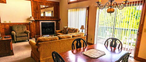 A living room with a fireplace, a dining table with chairs, a sofa, and a chair.