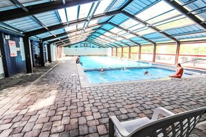 An indoor swimming pool with a tiled floor and a glass roof.