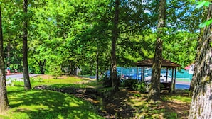 Um parque com um coreto, árvores e um riacho.