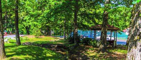 A park with a gazebo, trees, and a stream.