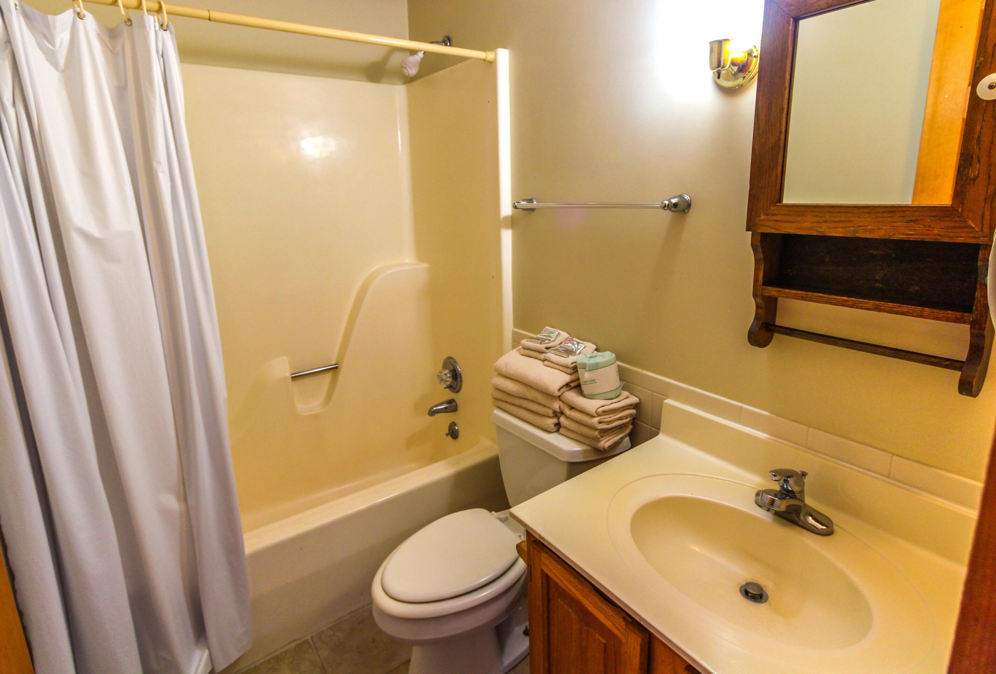 A bathroom with a bathtub, toilet, sink, and a mirror.