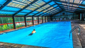 Piscina com cobertura, água cristalina e cadeira do salva-vidas.