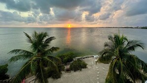 Una spiaggia con palme e un tramonto sull'acqua.