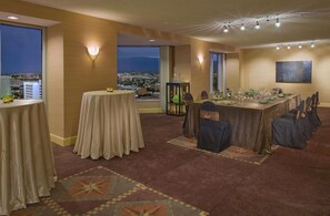 A dining area with a city view, tables set with glassware, and a large painting on the wall. - The Clyde Hotel (Albuquerque)