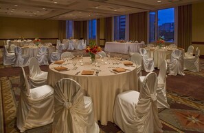 A banquet hall with round tables, white chairs, and floral centerpieces. - The Clyde Hotel (Albuquerque)