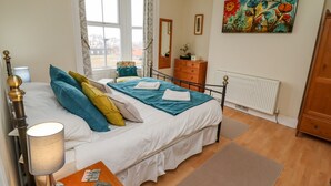 A bedroom with a bed, a dresser, a radiator, and a painting on the wall. - White Horses (Whitby)