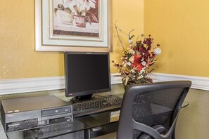 A computer desk with a monitor, keyboard, and printer. There is a chair in front of the desk. A framed picture hangs on the wall above the desk. - Days Inn by Wyndham Scottsboro AL (Scottsboro)