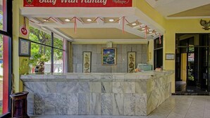 Un espace d’accueil d’hôtel avec un comptoir en marbre, des œuvres d’art encadrées accrochées aux murs et une enseigne indiquant le nom de l’hôtel.