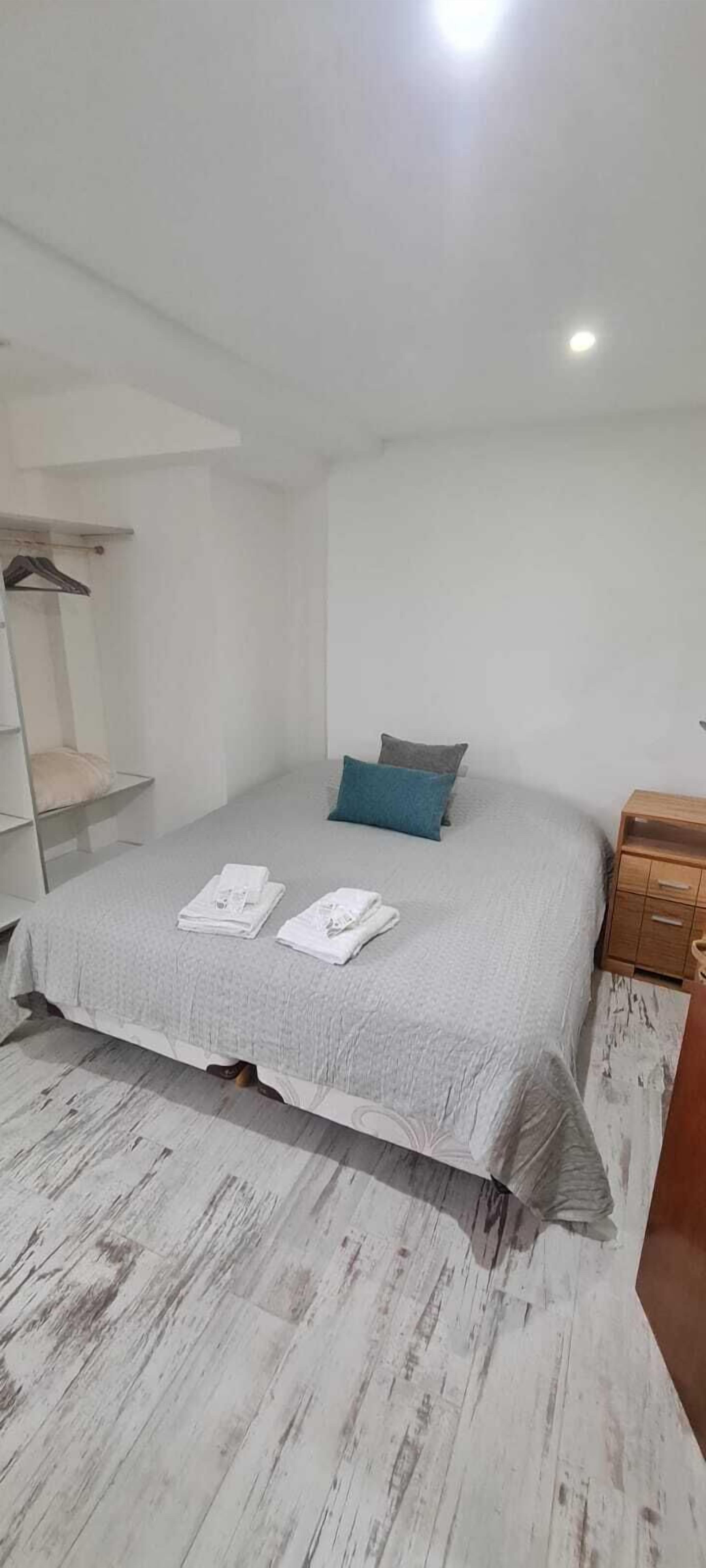 Un dormitorio con una cama, una mesita de noche y un armario.