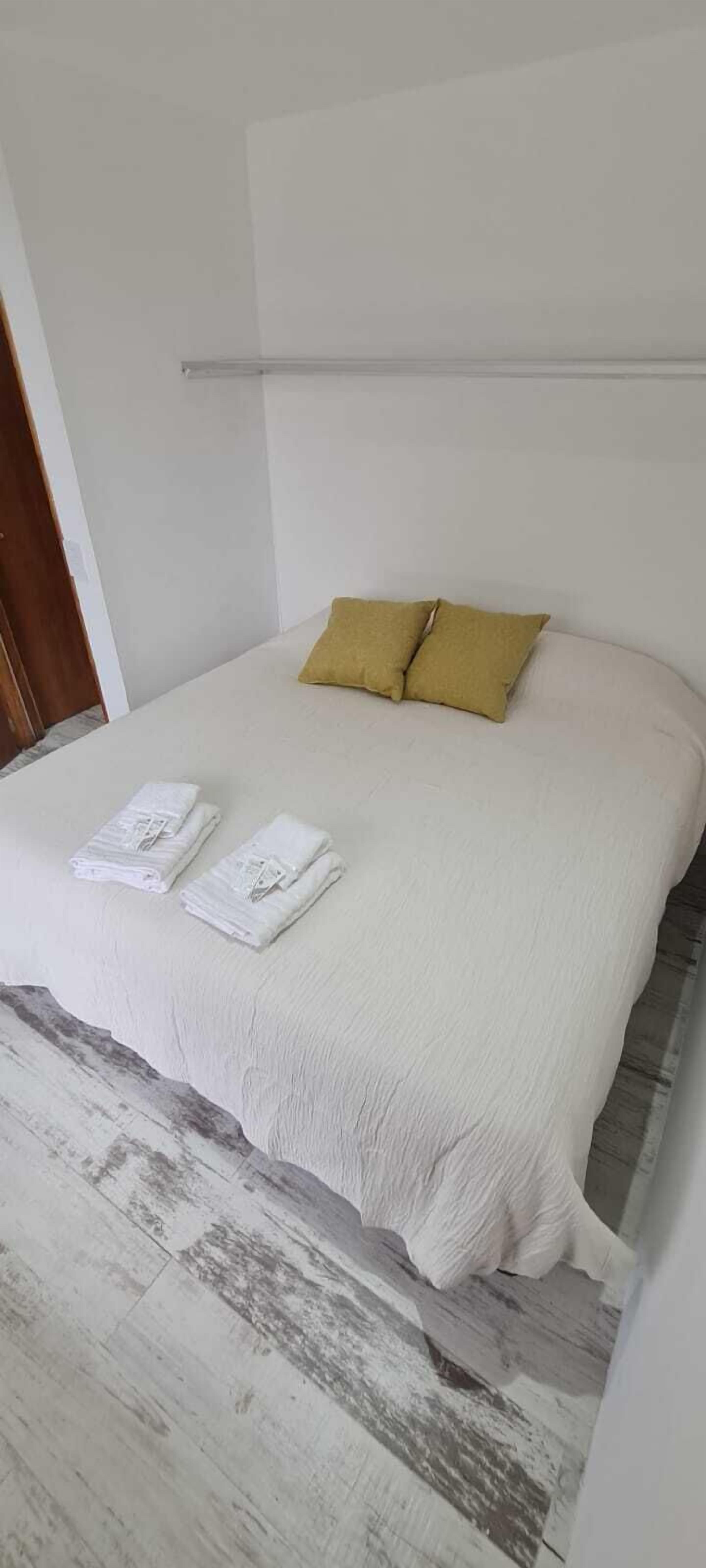 A bed with a white mattress, two pillows, and folded towels.